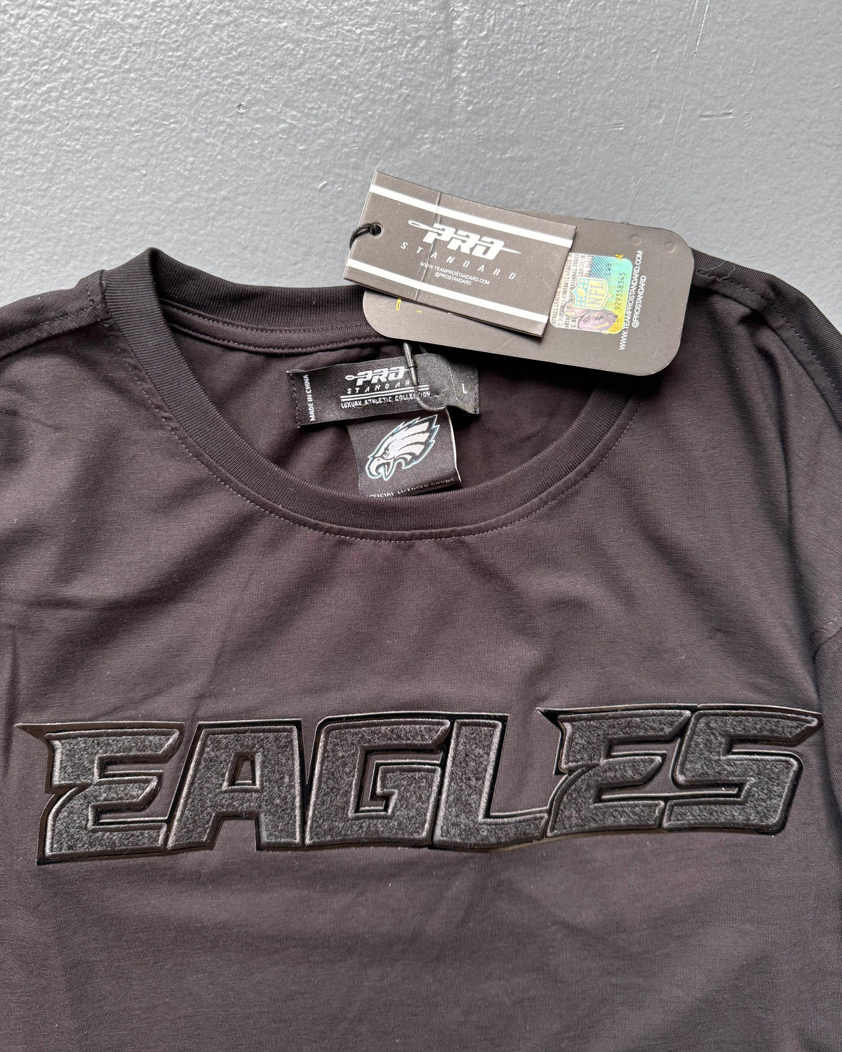 Black sports jersey with 'EAGLES' text and brand tags on a gray background